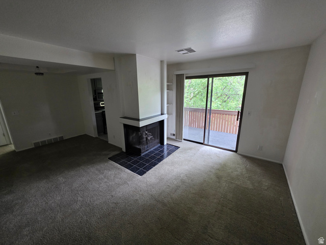 6852 Countrywoods Circle, Unit 5D Midvale, UT 84047 - Photo 8 of 50 Living area featuring a fireplace with a black tile hearth, built-in shelving, and carpet flooring