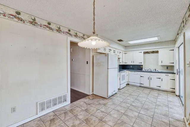 a large kitchen with white cabinets and white appliances