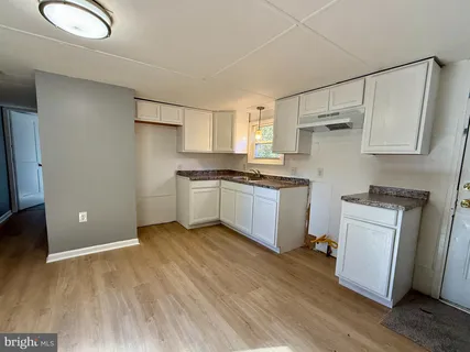 a kitchen with white cabinets and wooden floor