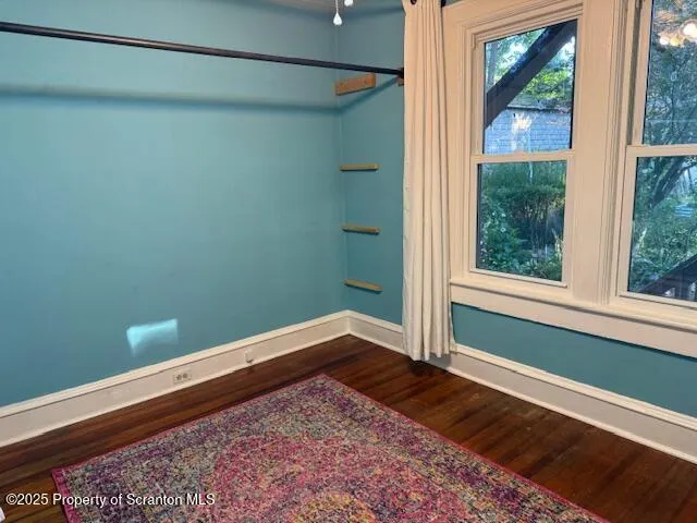 a view of empty room with window and wooden floor