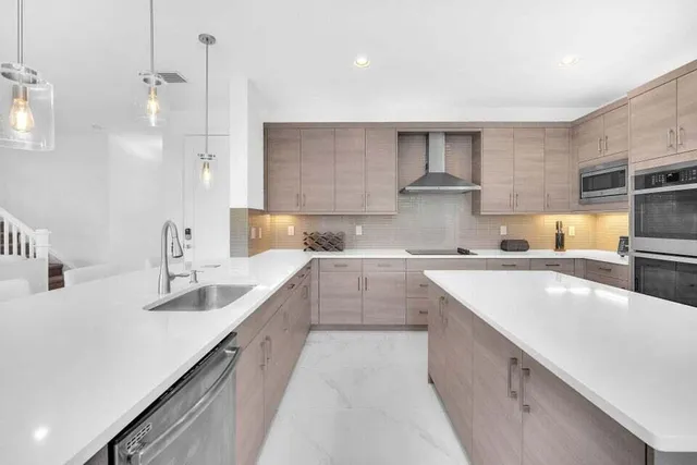 a kitchen with a sink a stove a refrigerator and white cabinets