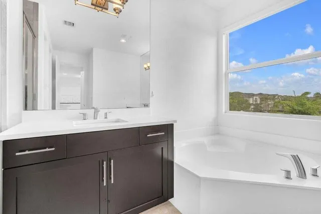a bathroom with a bathtub sink vanity and mirror