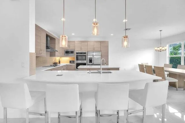 a kitchen with stainless steel appliances kitchen island granite countertop a table chairs and a refrigerator