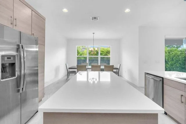 a dining room with stainless steel appliances a refrigerator a table a window and chairs