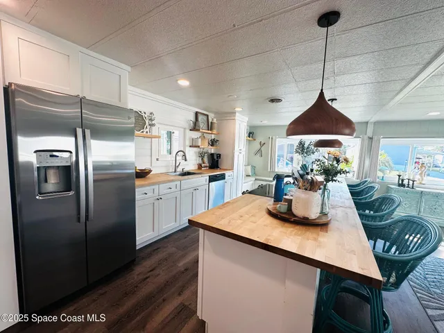 a kitchen with stainless steel appliances granite countertop a sink a refrigerator a stove a dining table and chairs