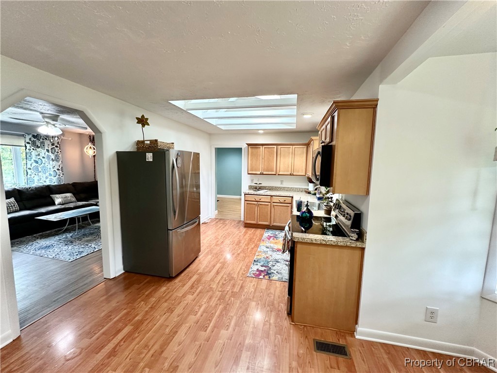 7809 Ark Road Gloucester, VA 23061 - Photo 7 of 32 Kitchen with stainless steel fridge, light wood-type flooring, and a skylight