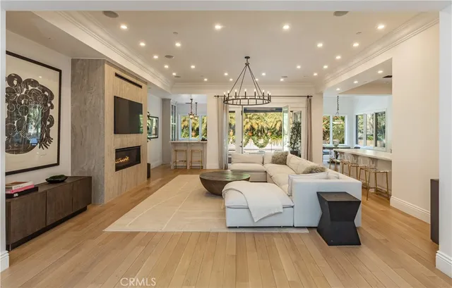 a living room with couches and kitchen view with wooden floor