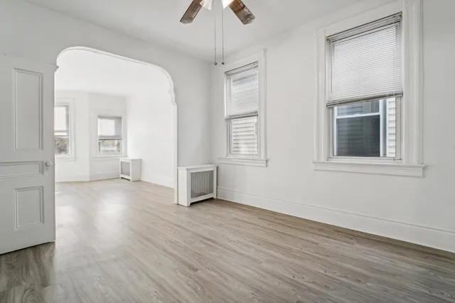 a view of an empty room with window and wooden floor