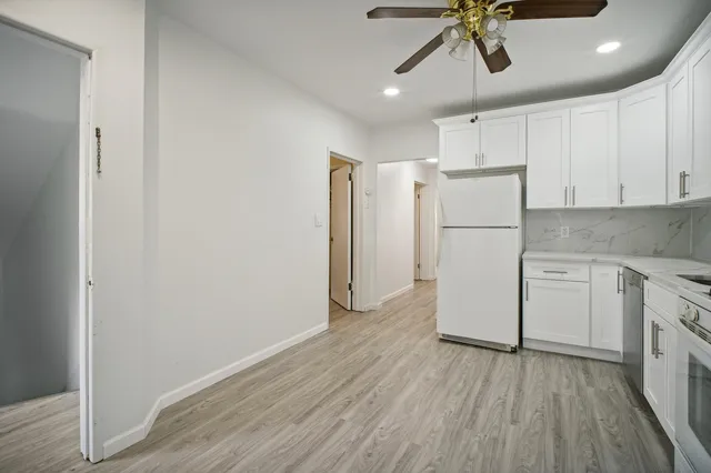 a view of a kitchen with a refrigerator a ceiling fan and wooden floor