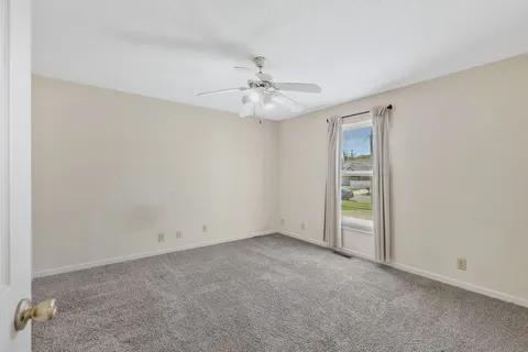 an empty room with windows and fan