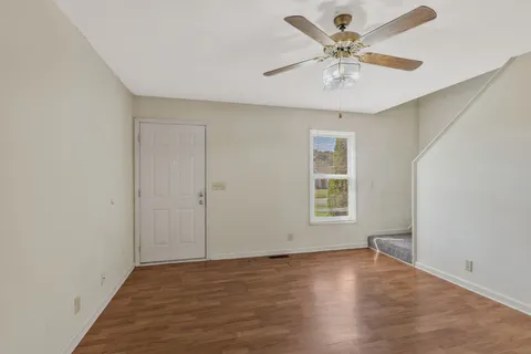 an empty room with wooden floor and windows
