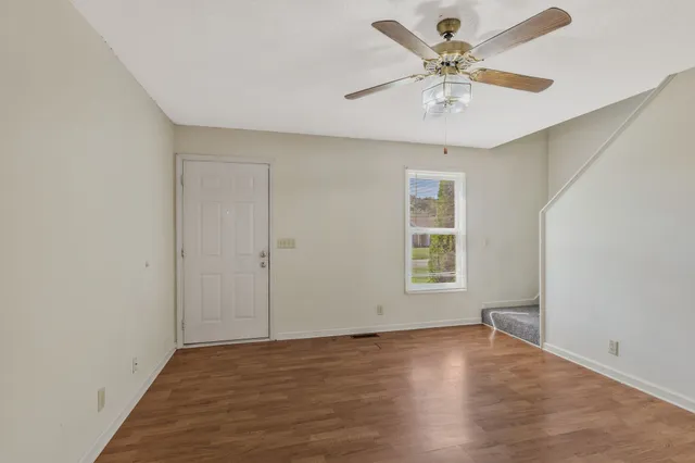 an empty room with wooden floor and windows