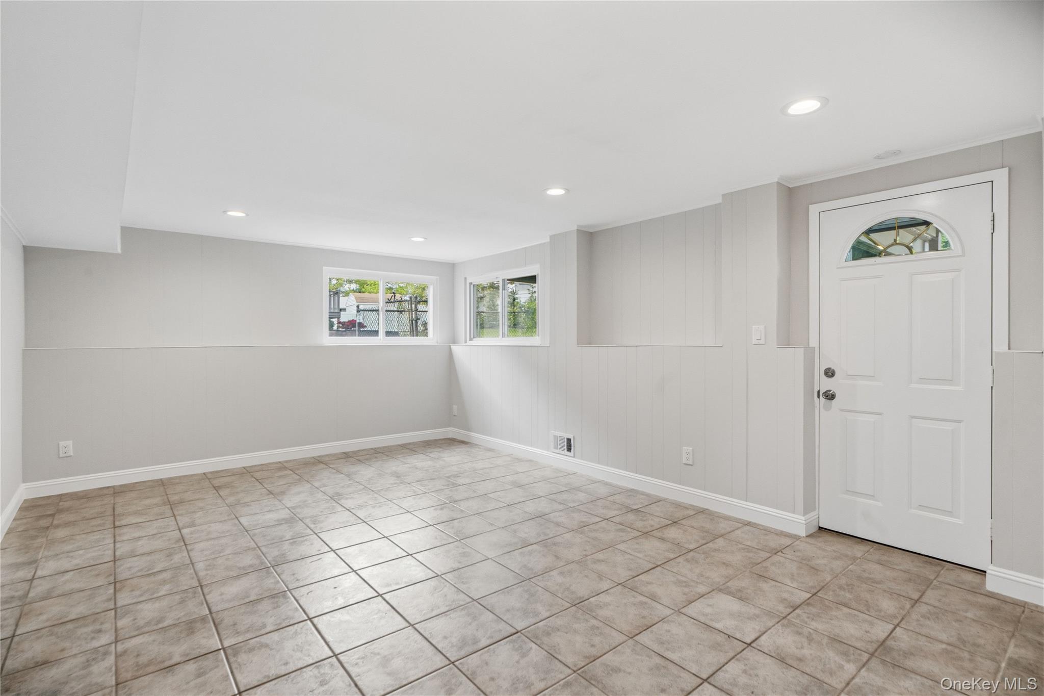 183 North Marginal Road Jericho, NY 11753 - Photo 21 of 28 First floor features a Spacious great room with neutral tone ceramic tile flooring and light gray walls with recessed lighting and door to backyard patio