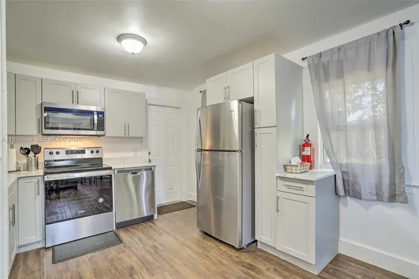 a kitchen with a refrigerator microwave and wooden floor