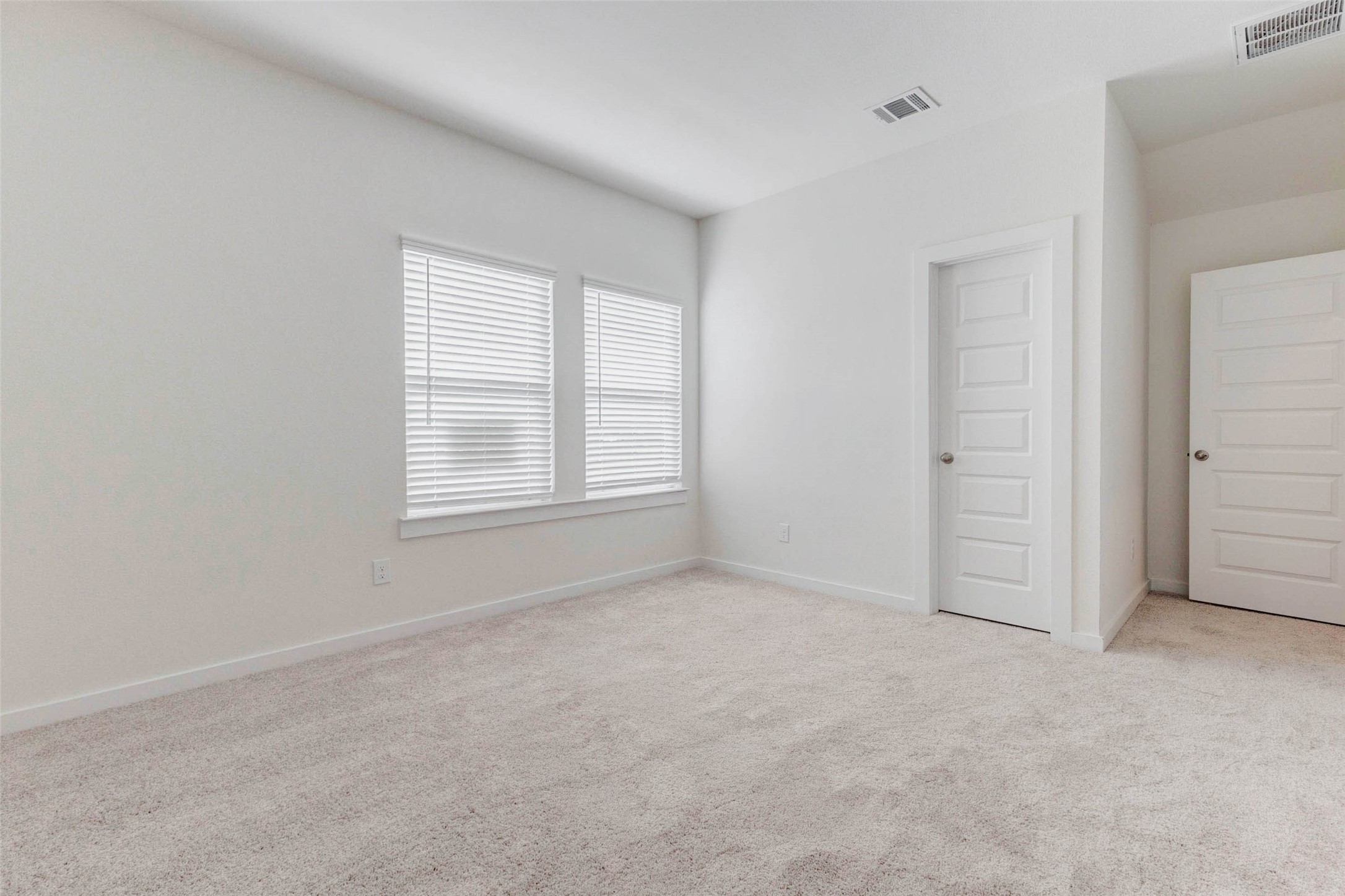 1131 Santee Court Rosharon, TX 77583 - Photo 19 of 31 Natural light floods this bedroom through two large windows, highlighting the neutral palette and plush carpeting. Complete with a closet and adjacent bath access, it’s ideal for a growing household or work-from-home office.