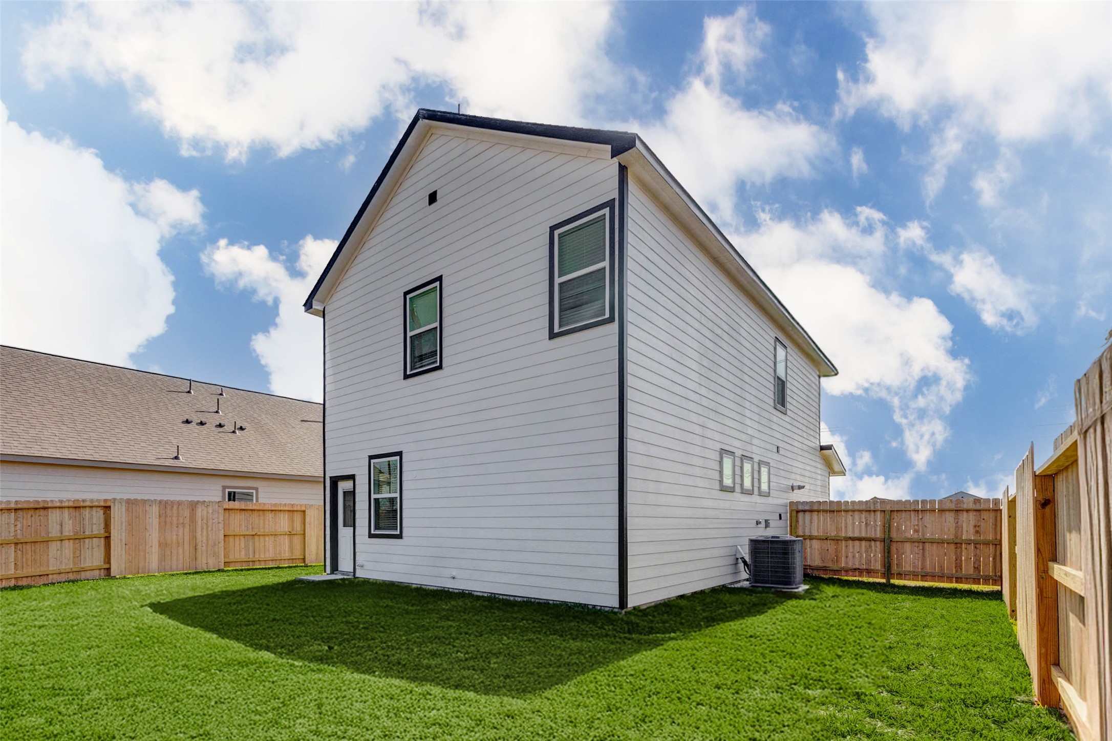 1131 Santee Court Rosharon, TX 77583 - Photo 29 of 31 A side view of the home’s rear elevation showcases its crisp horizontal siding, trimmed windows, and private rear entry. The yard wraps around, offering extra outdoor space, plus an exterior HVAC unit is positioned conveniently.