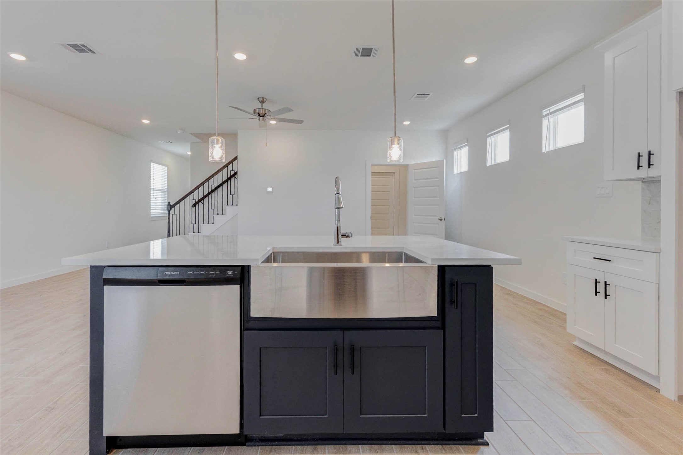 1131 Santee Court Rosharon, TX 77583 - Photo 10 of 31 The oversized quartz island with deep stainless farmhouse sink anchors the space and invites casual dining or meal prep. Pendant lighting adds a warm glow above, while the open layout connects directly to the living and dining areas for effortless flow.