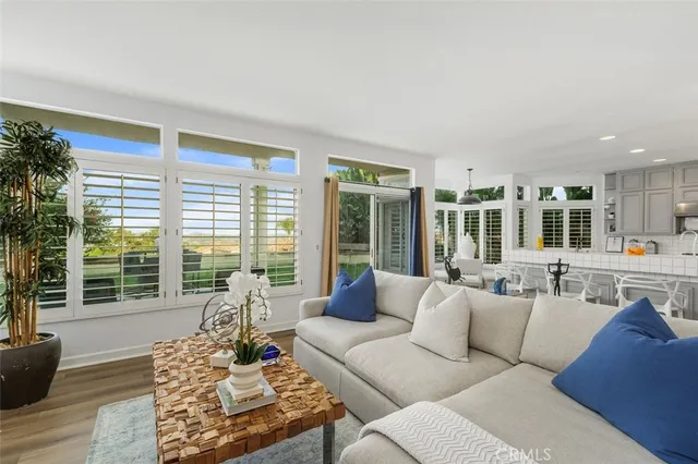 a living room with furniture large windows and wooden floor
