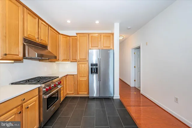 a kitchen with stainless steel appliances granite countertop a refrigerator a sink and wooden cabinets