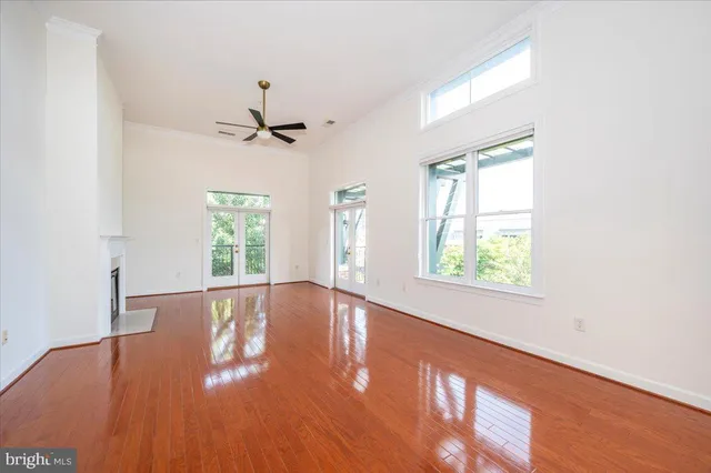 an empty room with wooden floor chandelier fan and windows