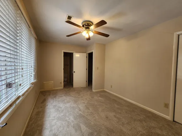 a view of an empty room with a ceiling fan and window