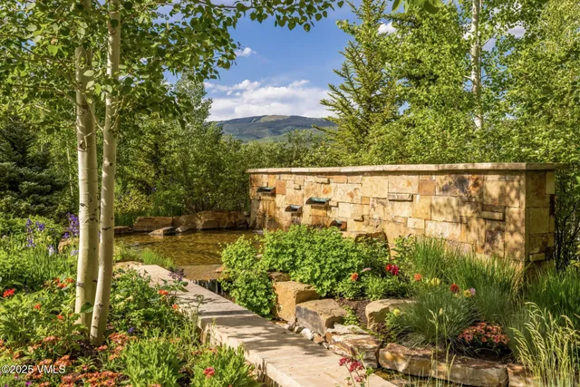 a living room with couches a flat screen tv and a large window with pool side view