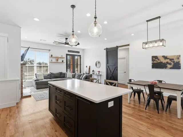 a large kitchen with a counter space a sink appliances and living room view