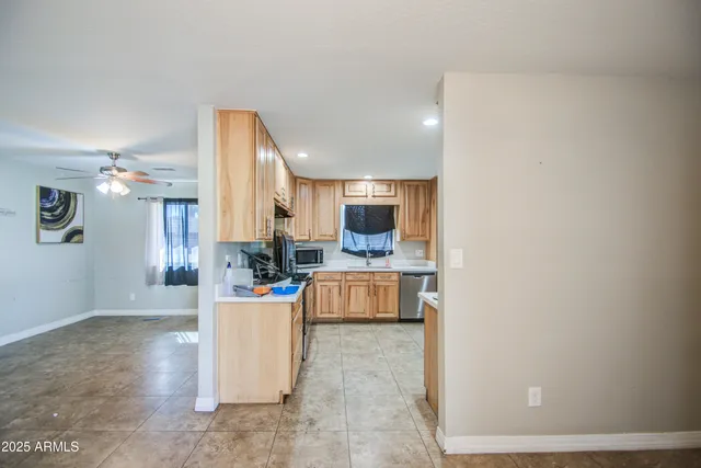 an empty room with a chandelier fan and wooden floor