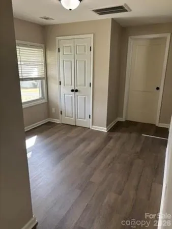 an empty room with wooden floor and windows