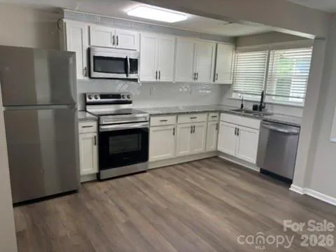 a kitchen with granite countertop stainless steel appliances a sink cabinets and a window
