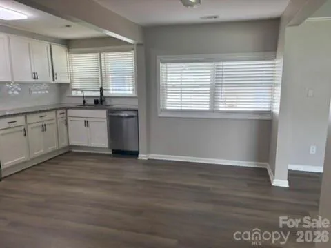 a kitchen with granite countertop a stove a sink and dishwasher wooden cabinets with wooden floor