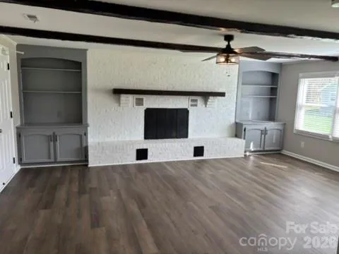 an empty room with windows and fireplace
