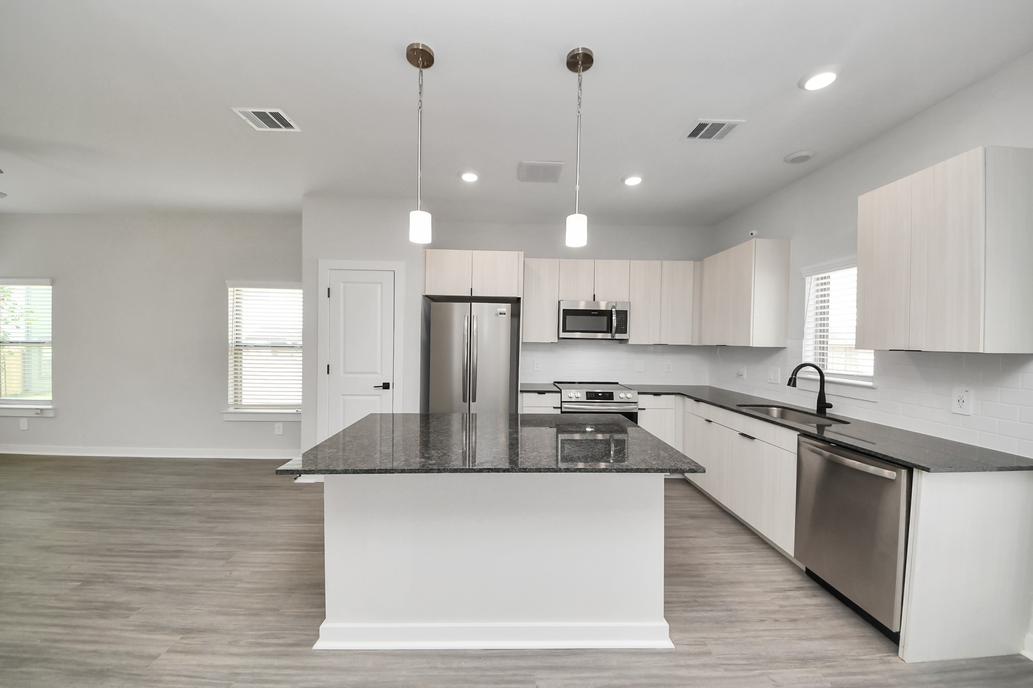 7711 Longmire Road, Unit 5 Conroe, TX 77304 - Photo 37 of 48 Boasting luxury finishes-stylish Island kitchen,granite counters,subway tile backsplash,ample custom cabinet space,stainless appliances,refrigerator,full size washer&dryer included,wood-like flooring throughout,open concept floor plan.