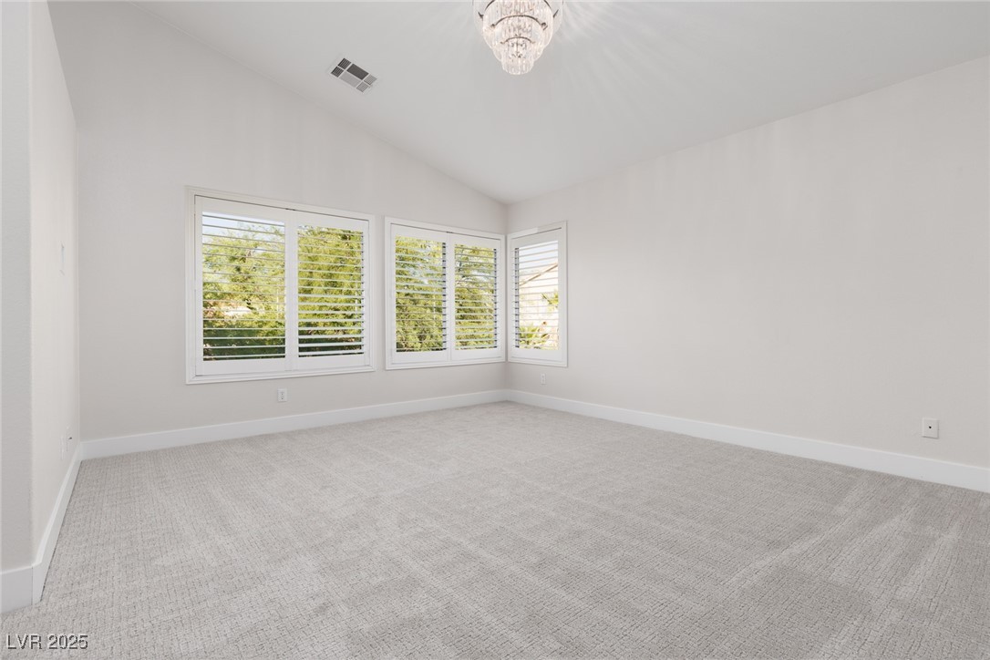 7837 Fort Ruby Place Las Vegas, NV 89128 - Photo 18 of 50 Unfurnished room with vaulted ceiling, light colored carpet, and a chandelier