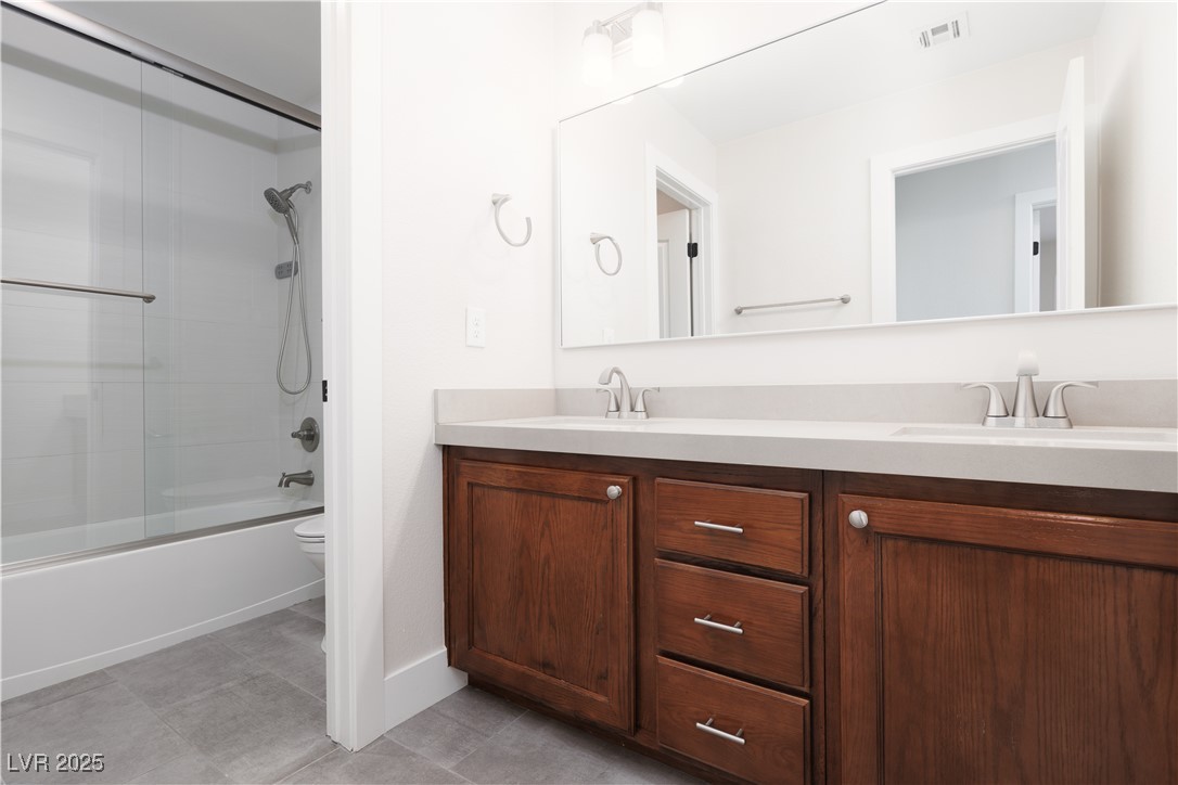 7837 Fort Ruby Place Las Vegas, NV 89128 - Photo 21 of 50 Bathroom with double vanity, enclosed tub / shower combo, toilet, and tile patterned floors