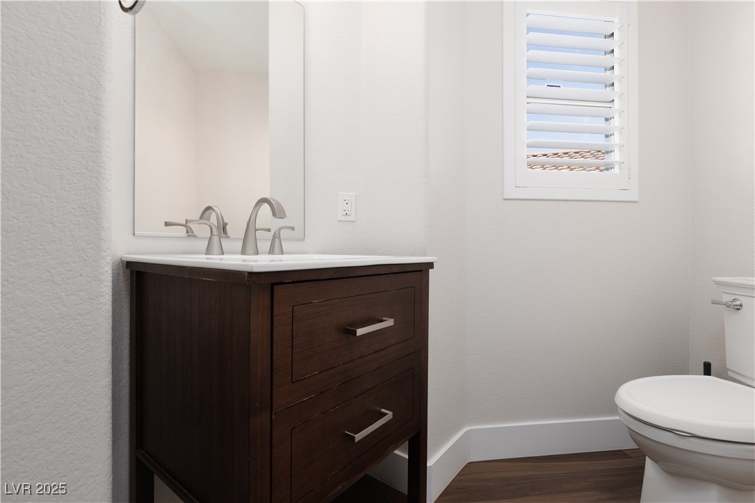 7837 Fort Ruby Place Las Vegas, NV 89128 - Photo 27 of 50 Downstairs Half bathroom with vanity, toilet, wood finished floors, and baseboards