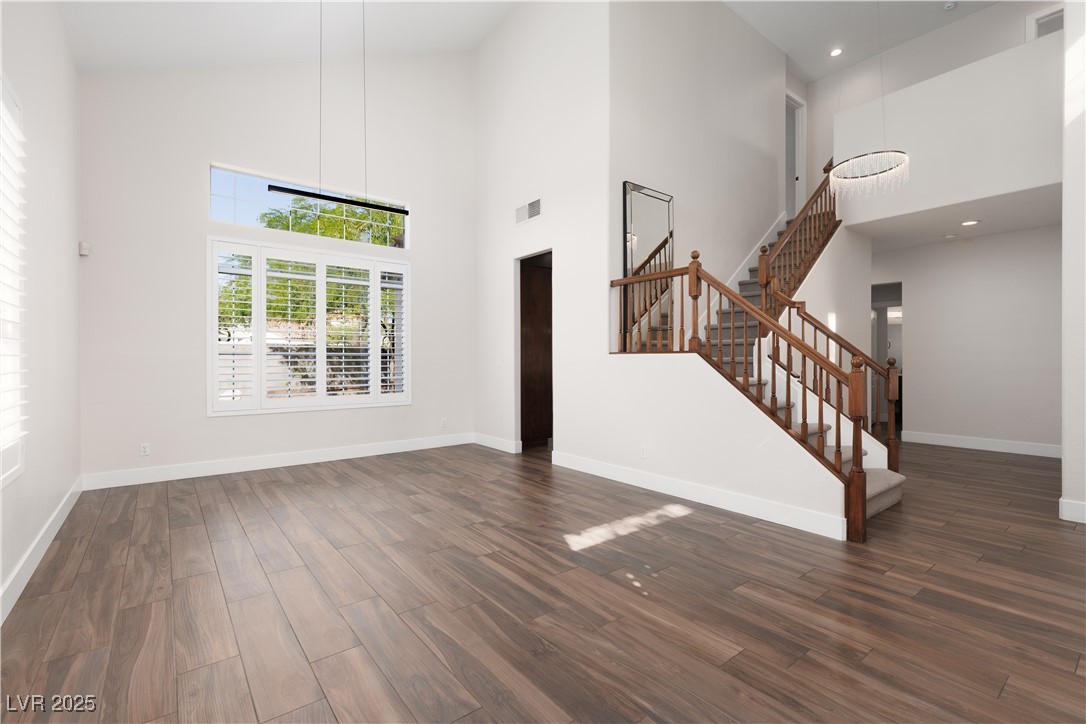 7837 Fort Ruby Place Las Vegas, NV 89128 - Photo 4 of 50 Unfurnished living room featuring a high ceiling, dark wood-style floors, stairs, and baseboards