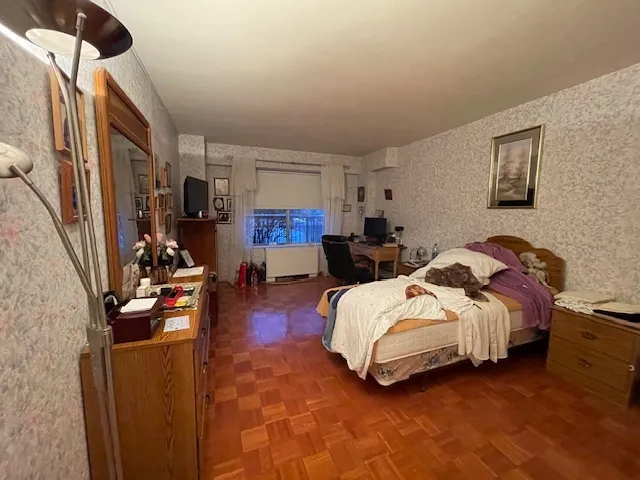 a spacious bedroom with bed and a flat tv screen
