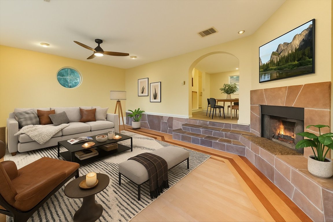 2405 Bahama Road Austin, TX 78733 - Photo 2 of 38 Living area featuring arched walkways, recessed lighting, a ceiling fan, a tiled fireplace, and wood finished floors