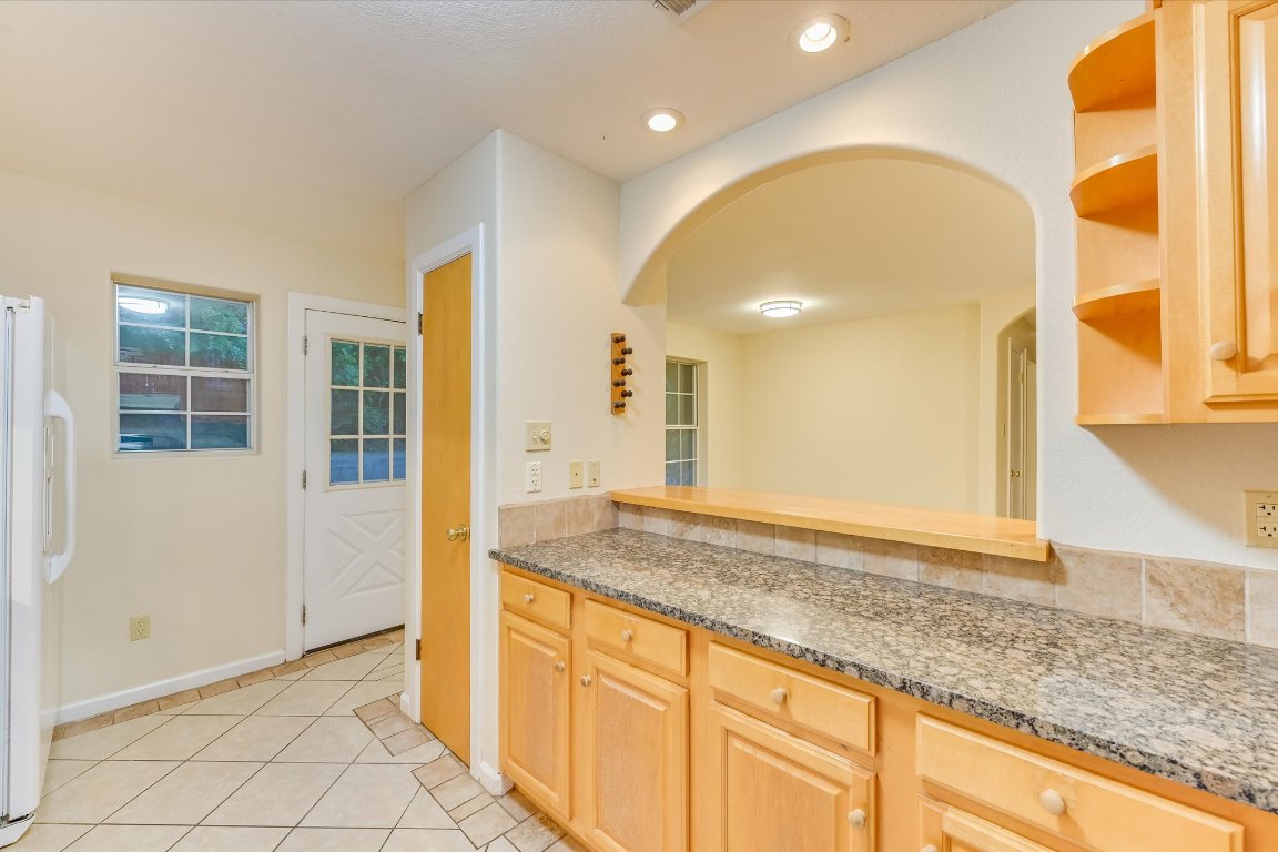 2405 Bahama Road Austin, TX 78733 - Photo 23 of 38 Kitchen featuring arched walkways, open shelves, light tile patterned floors, freestanding refrigerator, and light brown cabinetry