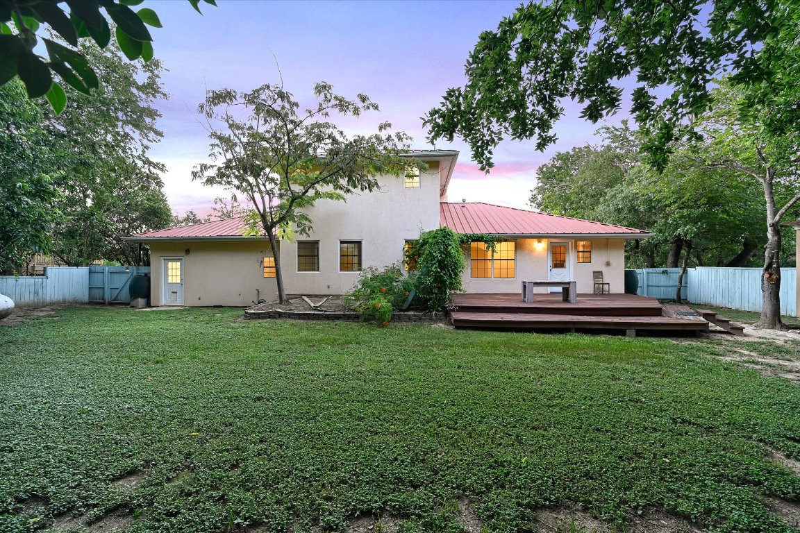 2405 Bahama Road Austin, TX 78733 - Photo 27 of 38 Back of house at dusk with a metal roof, a fenced backyard, a deck, and a standing seam roof
