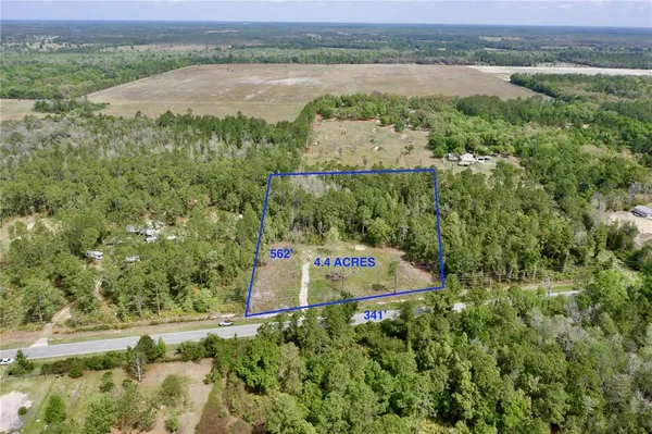 an aerial view of a residential houses with outdoor space and trees