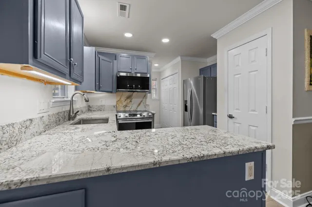 a kitchen with stainless steel appliances granite countertop a sink a stove and a refrigerator