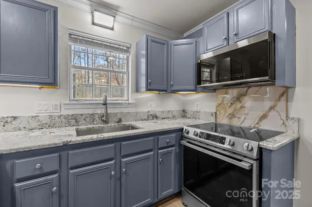 a kitchen with granite countertop a sink a stove and microwave