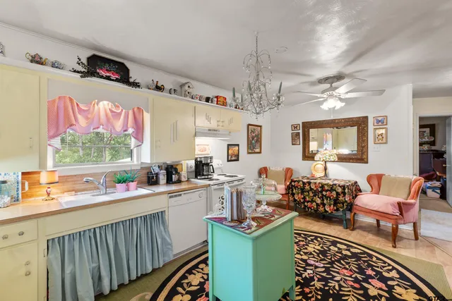 a kitchen with a sink dishwasher a dining table and chairs with wooden floor