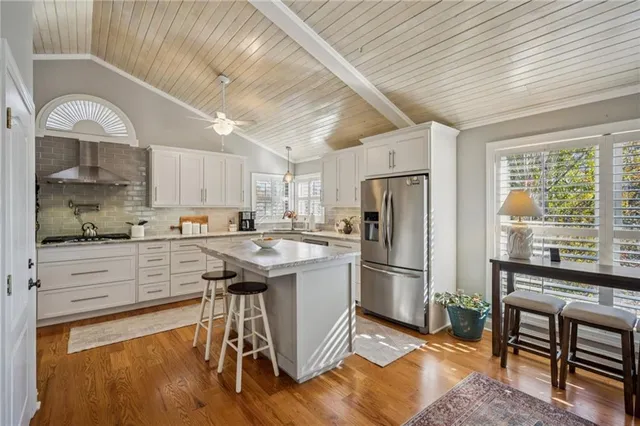 a kitchen with stainless steel appliances granite countertop a refrigerator a sink dishwasher a stove and white countertops with wooden floor