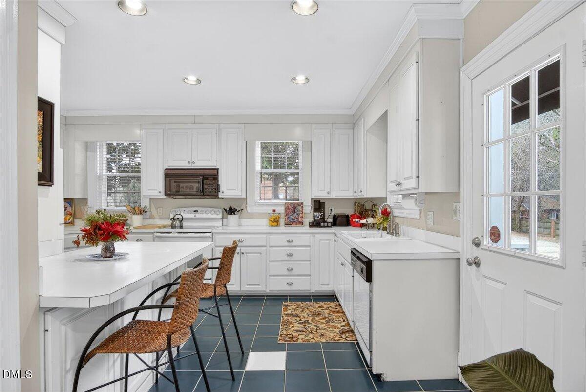 2064 Oxford Road Henderson, NC 27536 - Photo 16 of 68 a kitchen with a sink a stove cabinets and living room