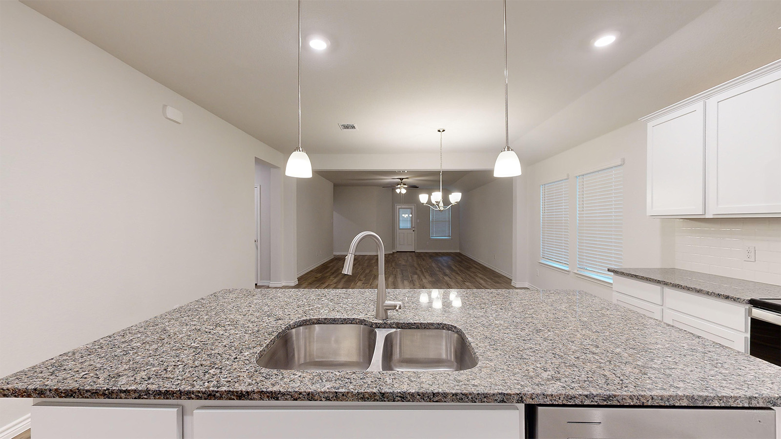 700 Gauge Road Thorndale, TX 76577 - Photo 5 of 22 Kitchen featuring white cabinets, a kitchen island with sink, light stone counters, hanging light fixtures, and recessed lighting