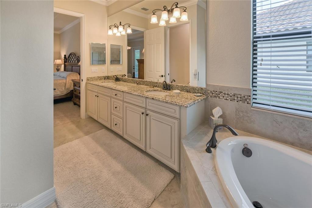 9387 Vercelli Court Naples, FL 34113 - Photo 12 of 25 a spacious bathroom with a granite countertop sink a mirror and a bathtub