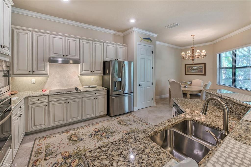 9387 Vercelli Court Naples, FL 34113 - Photo 6 of 25 a kitchen with granite countertop a refrigerator and a sink